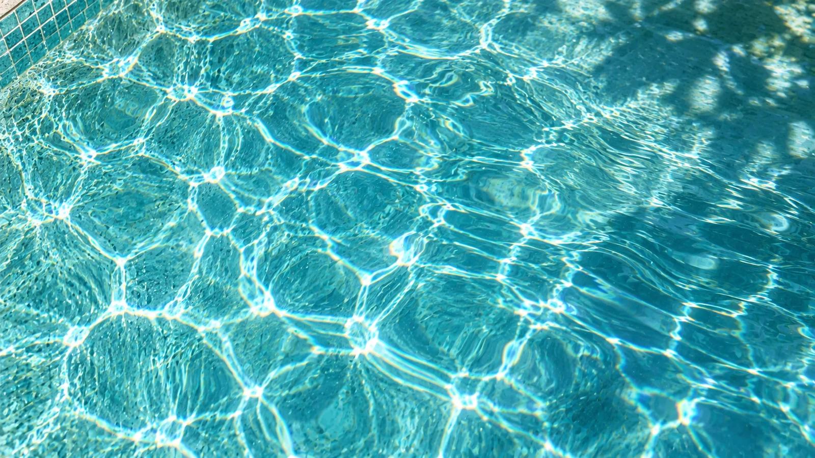 Sunlight drawing delicate patterns through clear turquoise pool water
